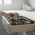 Go Hooked brown plastic drawer organizer filled with spice jars in a kitchen drawer.