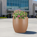 Go Hooked 20-inch brown polymer round planter with pink flowers, perfect for modern indoor or outdoor decor.