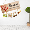 GoHooked brown MDF wood "This is Us" sign with red hearts and twine for hanging photos. Rustic farmhouse decor.