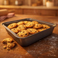 GoHooked carbon steel loaf pan filled with chocolate chip cookies, with a few cookies scattered on the wooden surface.