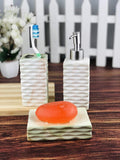 Go Hooked 3-piece ceramic bathroom set in Design-8, featuring a toothbrush holder, soap dispenser, and soap dish with an orange bar of soap.