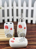 GoHooked white ceramic 3-piece bathroom set with red floral and grey leaf design. Includes soap dispenser, toothbrush holder, and soap dish.