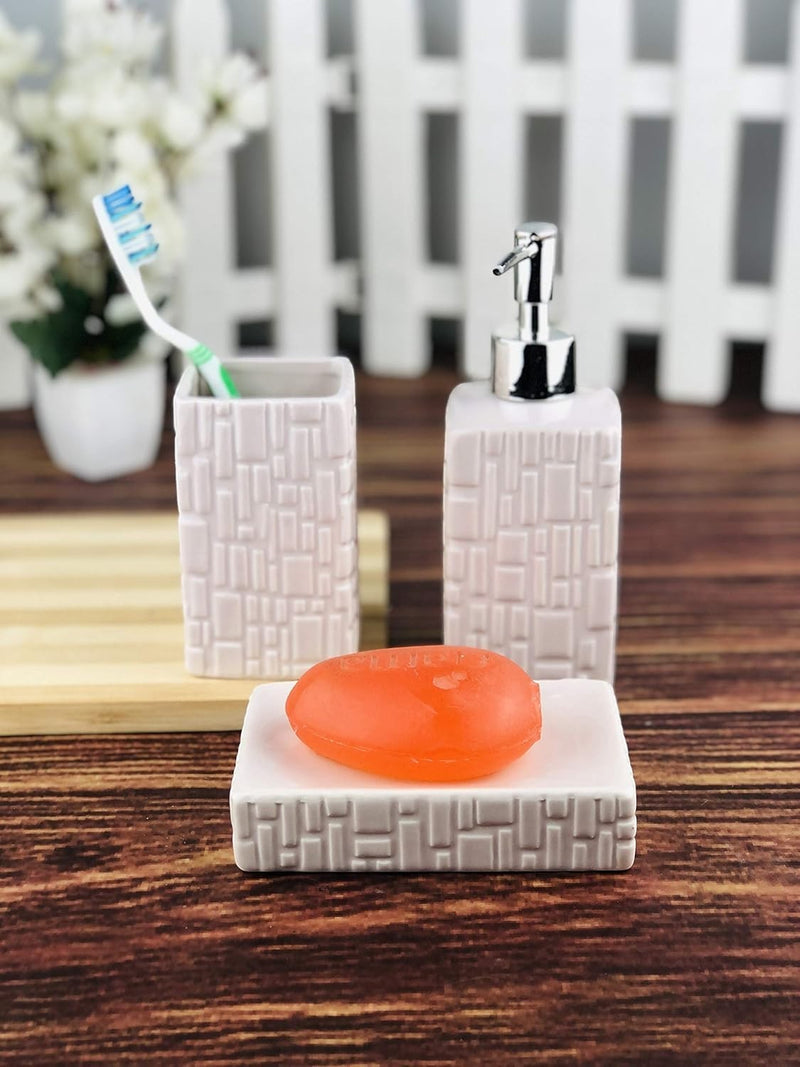 Go Hooked 3-piece ceramic bathroom set in light pink with textured geometric pattern. Includes soap dispenser, toothbrush holder, and soap dish with orange soap.