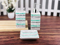 Go Hooked 3-piece ceramic bathroom set with toothbrush holder, soap dish, and dispenser. Features a white base with grey, teal, and white striped pattern.