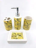 Go Hooked 4-piece ceramic bathroom set with yellow newspaper print and gun graphics. Includes soap dispenser, toothbrush holder, tumbler, and soap dish.