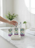 Go Hooked 4-piece ceramic bathroom set with floral pattern and purple base, includes soap dispenser, tumbler, toothbrush holder, and soap dish.