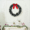 Go Hooked 20cm artificial pine Christmas wreath with red bow, green and white tinsel, indoor wall decor.
