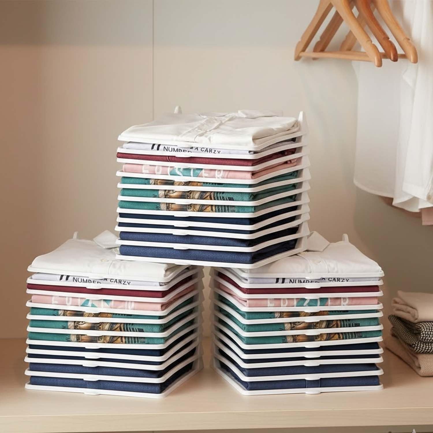 GoHooked white plastic stackable clothes organizer trays neatly holding folded shirts and tops in a closet.