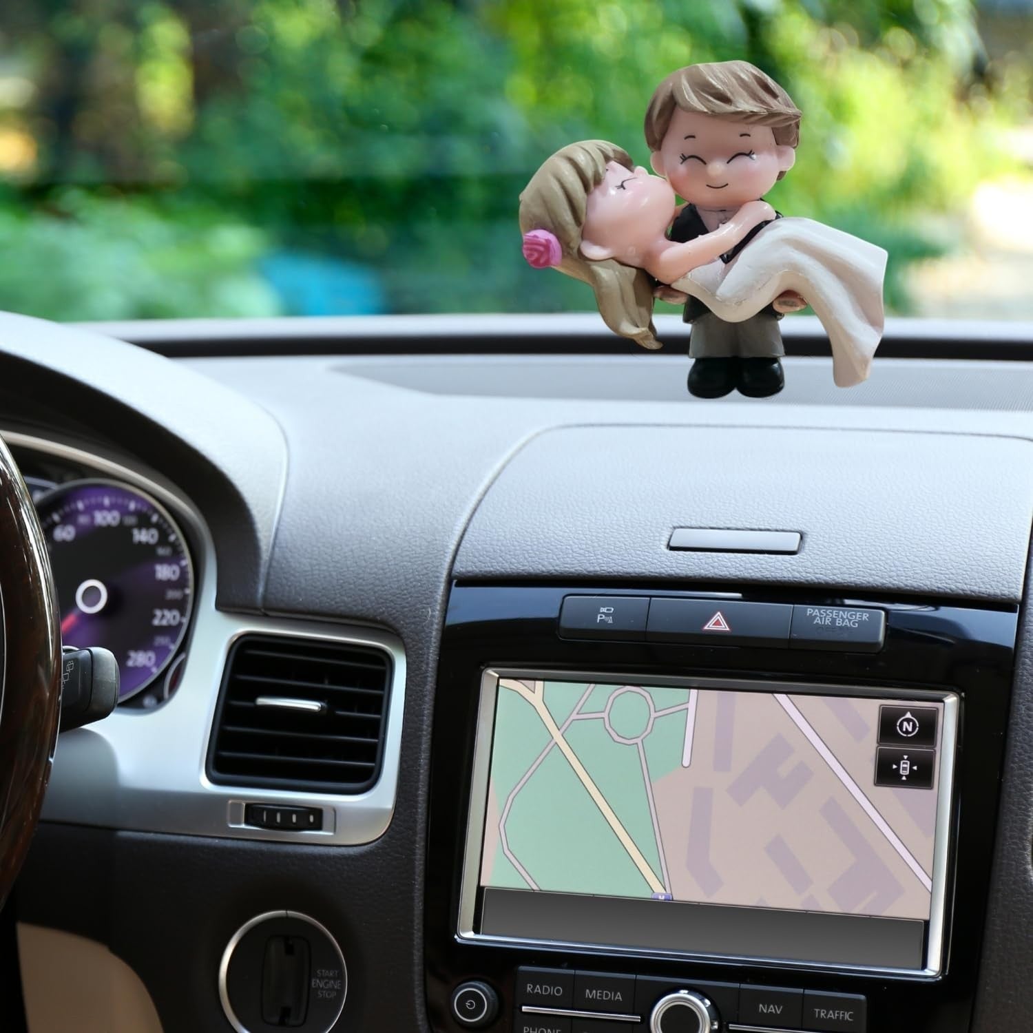 Go Hooked romantic bride and groom figurines in black and white, made of resin, kissing on a car dashboard.