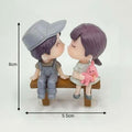 GoHooked resin couple figurines kissing on a bench, girl holds pink bunny. Romantic decor.