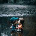 GoHooked resin couple figurines kissing on a bench in the rain, wearing blue cap and pink dress.
