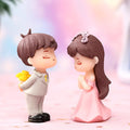 Go Hooked resin couple figurines, boy in suit with flowers, girl in pink dress, romantic proposal scene.
