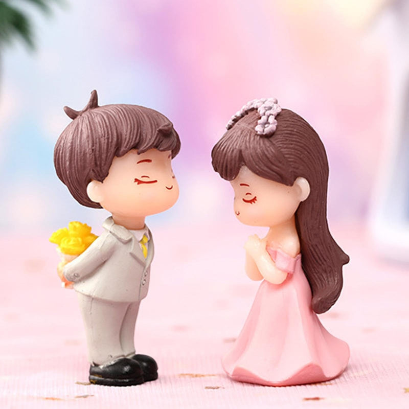 Go Hooked resin couple figurines, boy in suit with flowers, girl in pink dress, romantic proposal scene.