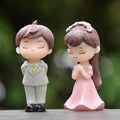 Go Hooked resin couple figurines in proposal pose. Groom in white suit, bride in pink dress. Romantic gift for couples.