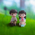 Go Hooked romantic couple figurines sitting on grass, girl holds pink cup. Resin, blue dress.