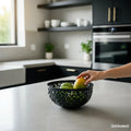 GoHooked dark grey plastic fruit bowl with intricate cutout design, holding mangoes and apples on a kitchen counter.