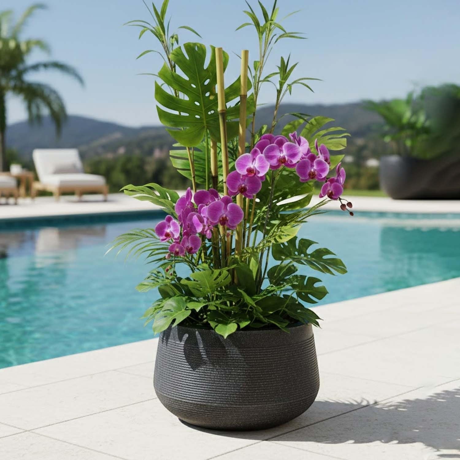 Go Hooked 15 inch dark grey textured polymer planter with purple orchids and tropical foliage by a pool.