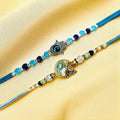 GoHooked designer rakhis with blue beads, Hamsa hand charm, and sun face charm on gold fabric.