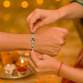 GoHooked designer Rakhi with pearl beads and peacock motif, tied on a brother's wrist during Raksha Bandhan.