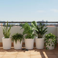 Go Hooked white Eiffel Tower 14-inch plastic planter pot with ribbed design, holding various indoor plants on a balcony.