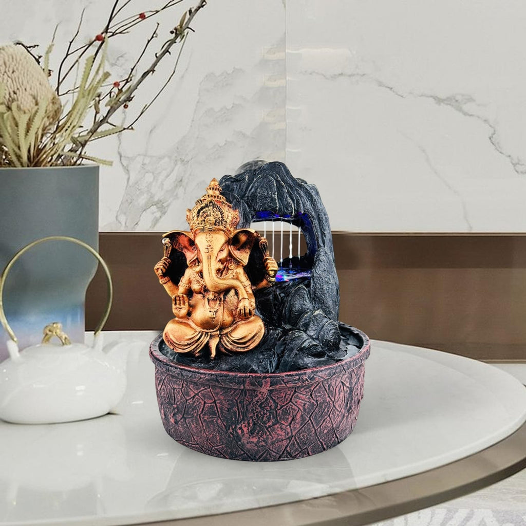 GoHooked Lord Ganesha polyresin tabletop fountain with LED lights and adjustable water flow. Bronze Ganesha sits in front of a dark rock waterfall.