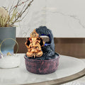 GoHooked Lord Ganesha polyresin tabletop fountain with LED lights and adjustable water flow. Bronze Ganesha sits in front of a dark rock waterfall.