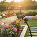 GoHooked green 7-pattern garden hose sprayer watering pink roses in a garden at sunset.
