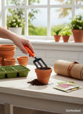 Go Hooked orange and black metal gardening fork with plastic handle, used to aerate soil in a terracotta pot.