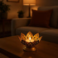 GoHooked gold metal lotus tealight holder with a lit candle, casting intricate shadows. Ideal for Diwali decor.
