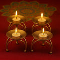 Go Hooked set of 4 matte gold metal pedestal tealight candle holders with burning candles.
