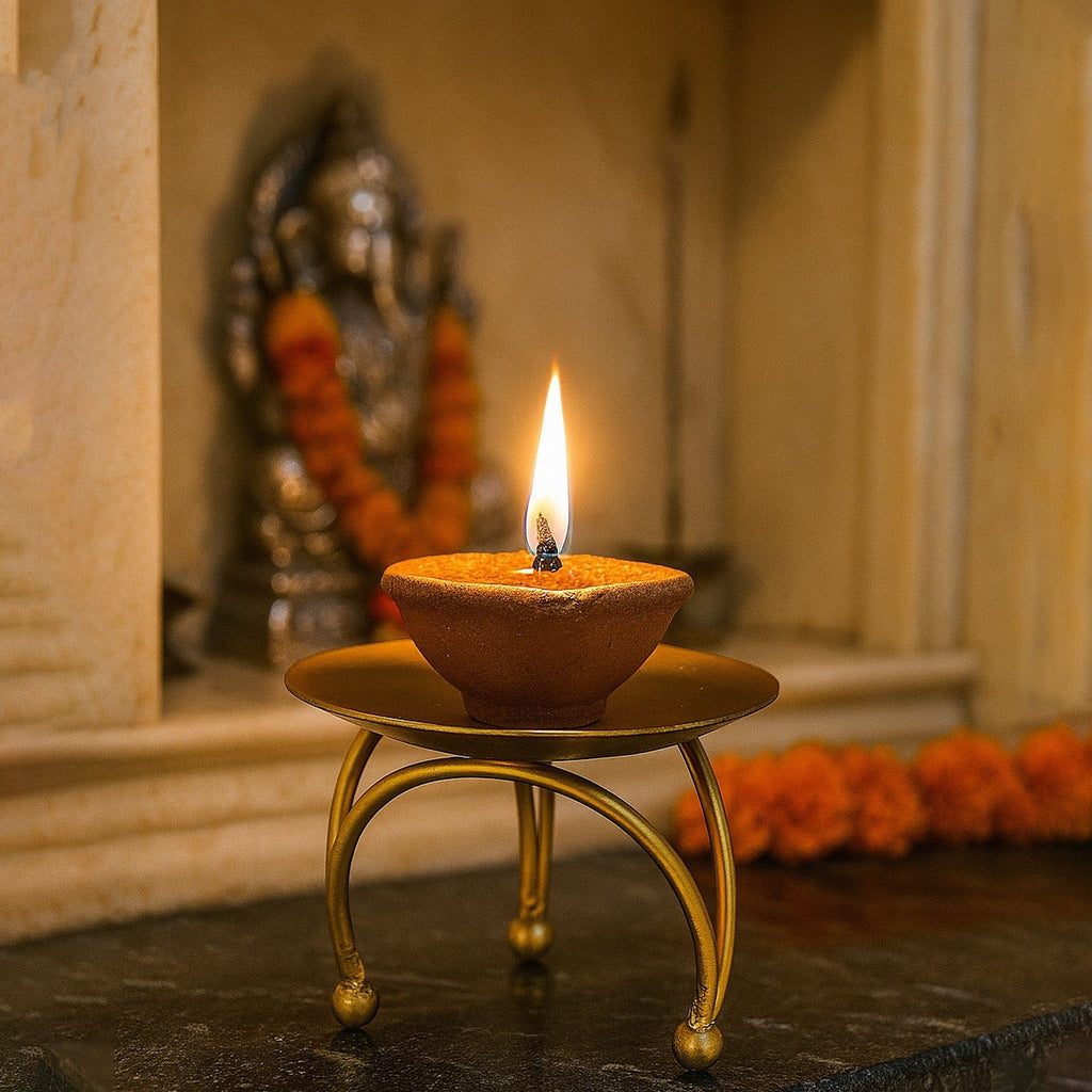 GoHooked gold metal pedestal tealight candle holder with a lit diya, featuring a tripod base and decorative ball feet.