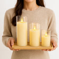 GoHooked set of 3 golden acrylic LED tea light candles with flickering flame effect in glass holders on a wooden tray.
