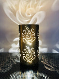 Go Hooked golden metal table lamp with Ganesha cutouts, casting decorative shadows. Ideal for bedrooms and living rooms.