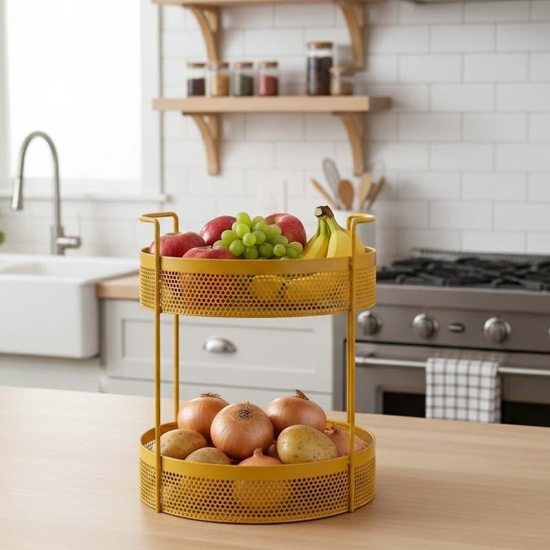 Go Hooked golden metal 2-tier mesh basket filled with apples, grapes, bananas, onions, and potatoes on a kitchen counter.
