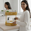 Go Hooked golden metal 2-tier countertop storage basket with mesh design holding toiletries and towels.