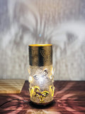 Go Hooked golden metal bedside table lamp with intricate butterfly cutouts and a warm yellow light, casting decorative shadows.