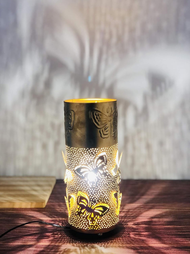 Go Hooked golden metal bedside table lamp with intricate butterfly cutouts and a warm yellow light, casting decorative shadows.
