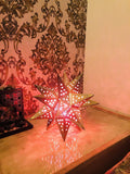Go Hooked golden metal star-shaped table lamp with cut-out star patterns, casting a warm glow.