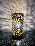 GoHooked golden metal bedside table lamp with intricate geometric cutouts casting starburst shadows.