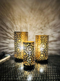 GoHooked Set of 3 golden metal table lamps with intricate star cutouts, casting decorative shadows. Art Deco style.