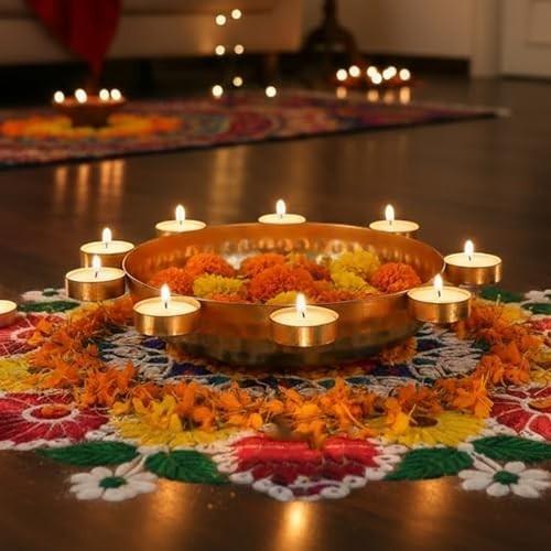 Go Hooked golden metal urli bowl with peacock motifs, filled with orange and yellow flowers, surrounded by tealights and marigold petals.