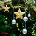 Go Hooked golden star and silver ball Christmas ornaments hanging on a mossy tree branch.