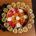 GoHooked handcrafted golden metal urli bowl with rose border, filled with water, floating candles, red rose petals, and marigolds.