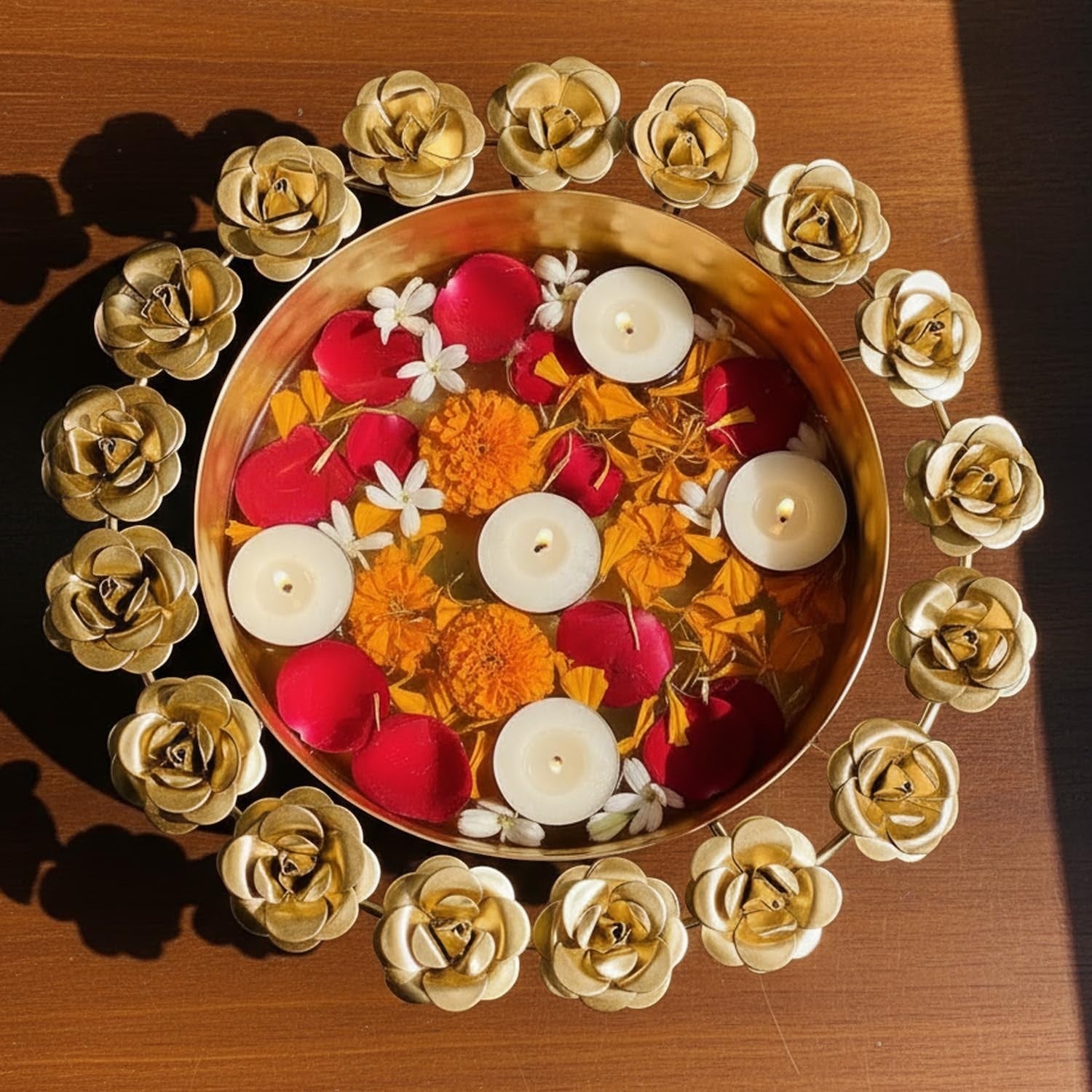 GoHooked handcrafted golden metal urli bowl with rose border, filled with water, floating candles, red rose petals, and marigolds.