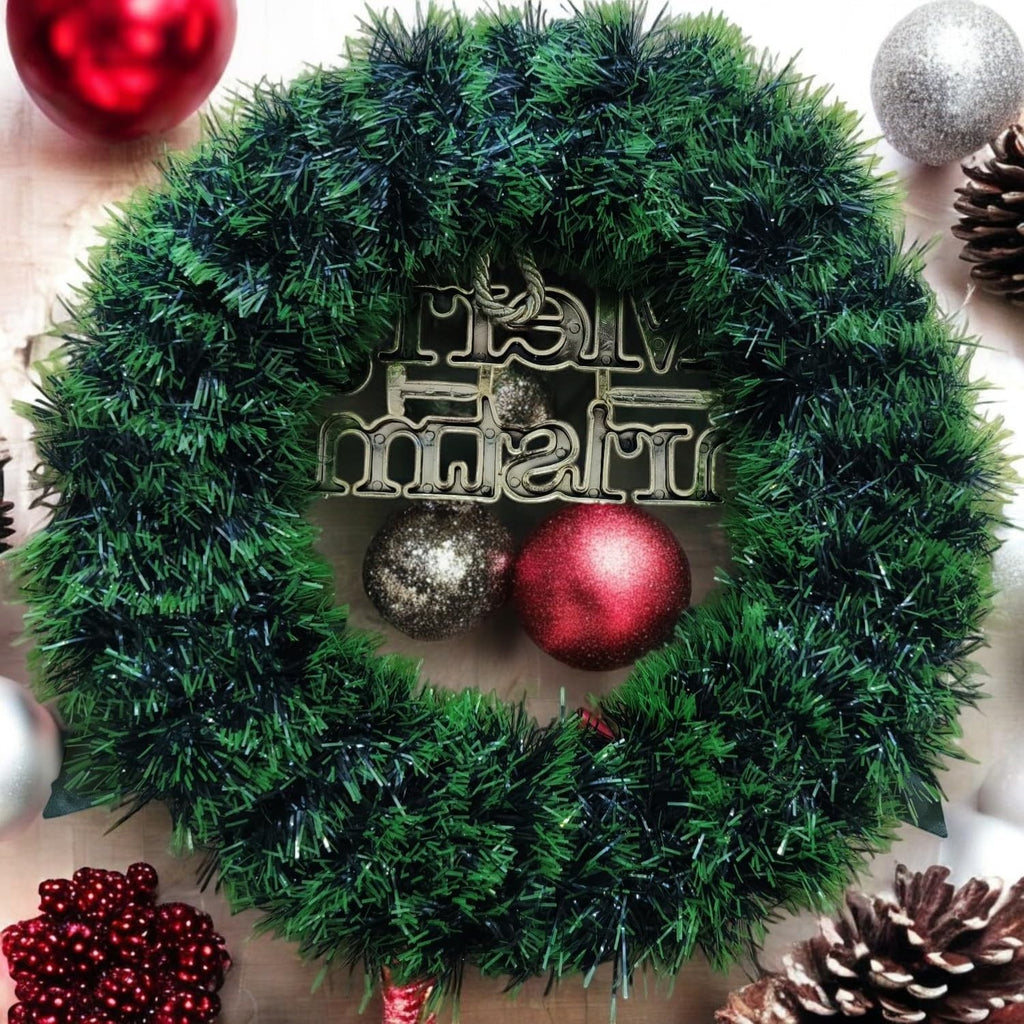 GoHooked green tinsel Christmas wreath with "Merry Christmas" sign, red and silver baubles, pinecones, and berries.