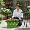 Go Hooked 12-inch green metal oval planter with white polka dots, holding plants on a deck.
