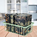 GoHooked green metal wire grid basket holding two black gift-wrapped packages with gold snowflakes and ornaments.