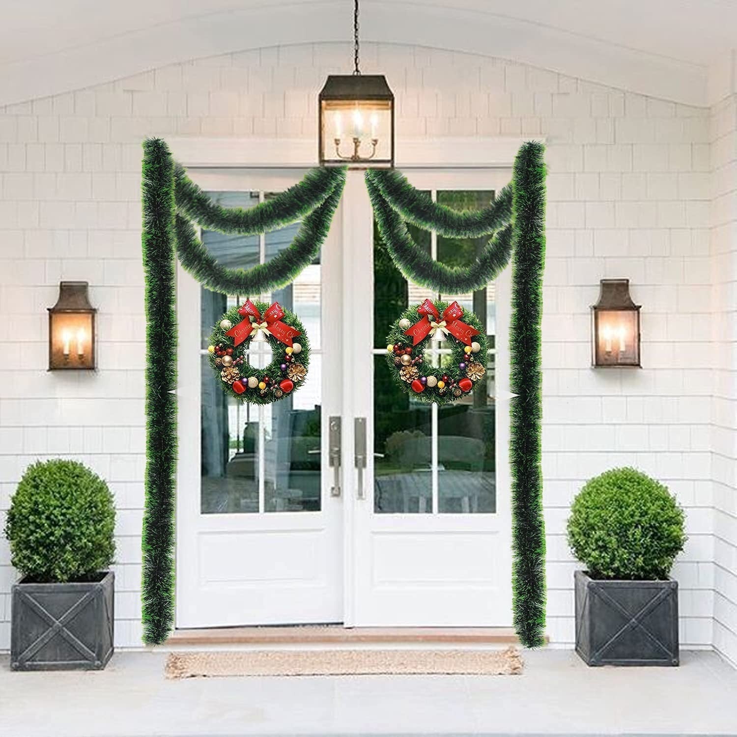 GoHooked Set of 3 green plastic tinsel garlands draped around a white double door with two wreaths. Festive Christmas decor.