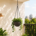 Go Hooked grey textured polymer hanging planter pot with metal chain, holding a lush green plant on a balcony.