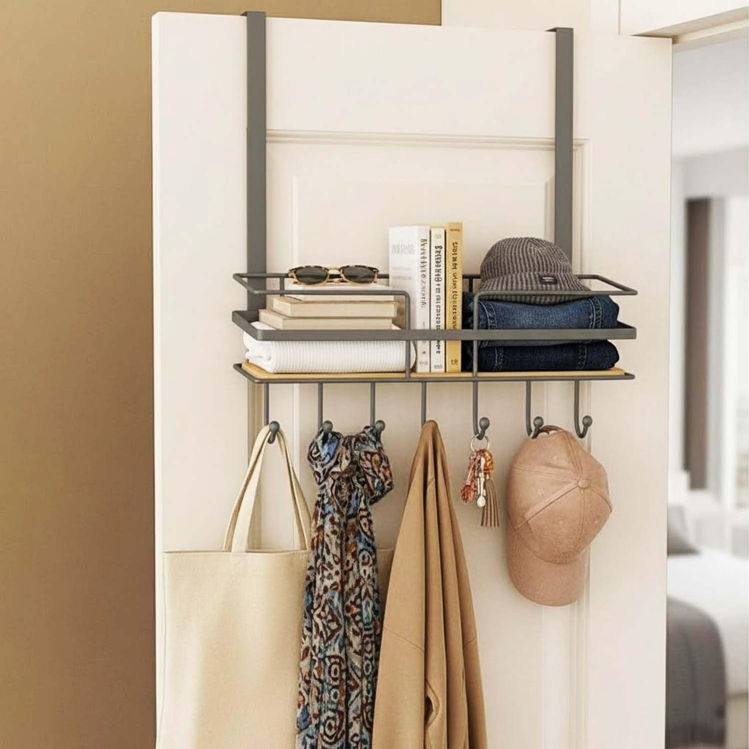 GoHooked grey metal over-door organizer with wooden shelf, 5 hooks, holding books, sunglasses, hat, jeans, scarf, coat, and bag.